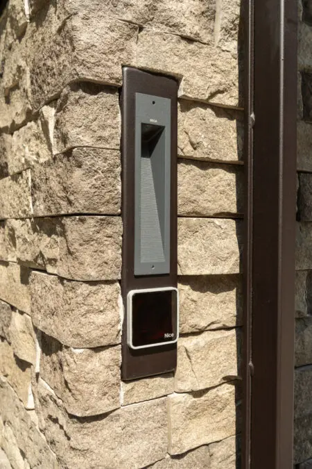 Intercom verwerkt in pilaar met hekwerk. Omgeven met Graffio Geopietra steenstrips Kleur BM