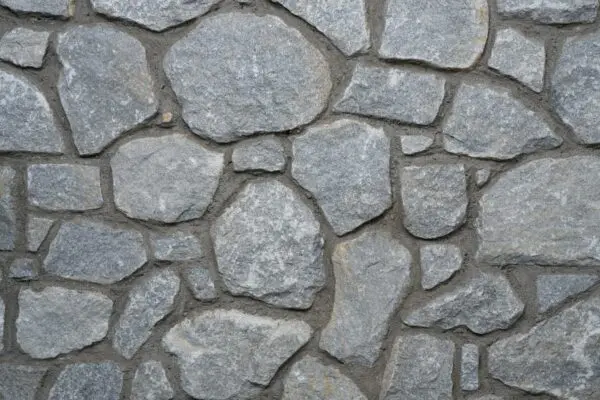Grijze natuurstenen muur in wildverband met subtiele kleurvariatie en ruwe structuur.