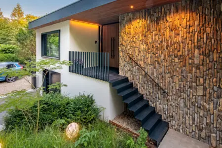 Verticale natuursteen toegepast aan de buitengevel bij de entree en buitentrap van een moderne woning.