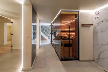Lange hal met glazen sauna met uitzicht op de stenen verticale muur bedekt met Geopietra Steenstrips