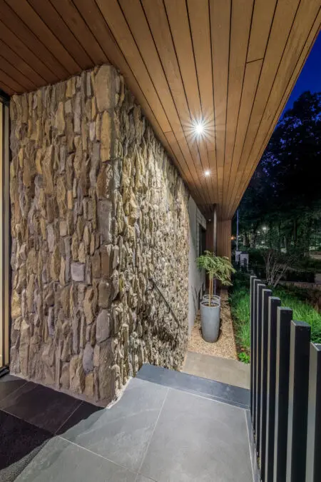 Verticale natuursteen toegepast op een buitenmuur als accent, gecombineerd met moderne tuinarchitectuur.