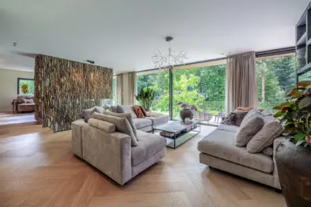 inrichting woonkamer met stoelen banken salontafel en stenen wand bekleed met verticale Geopietra Steenstrips