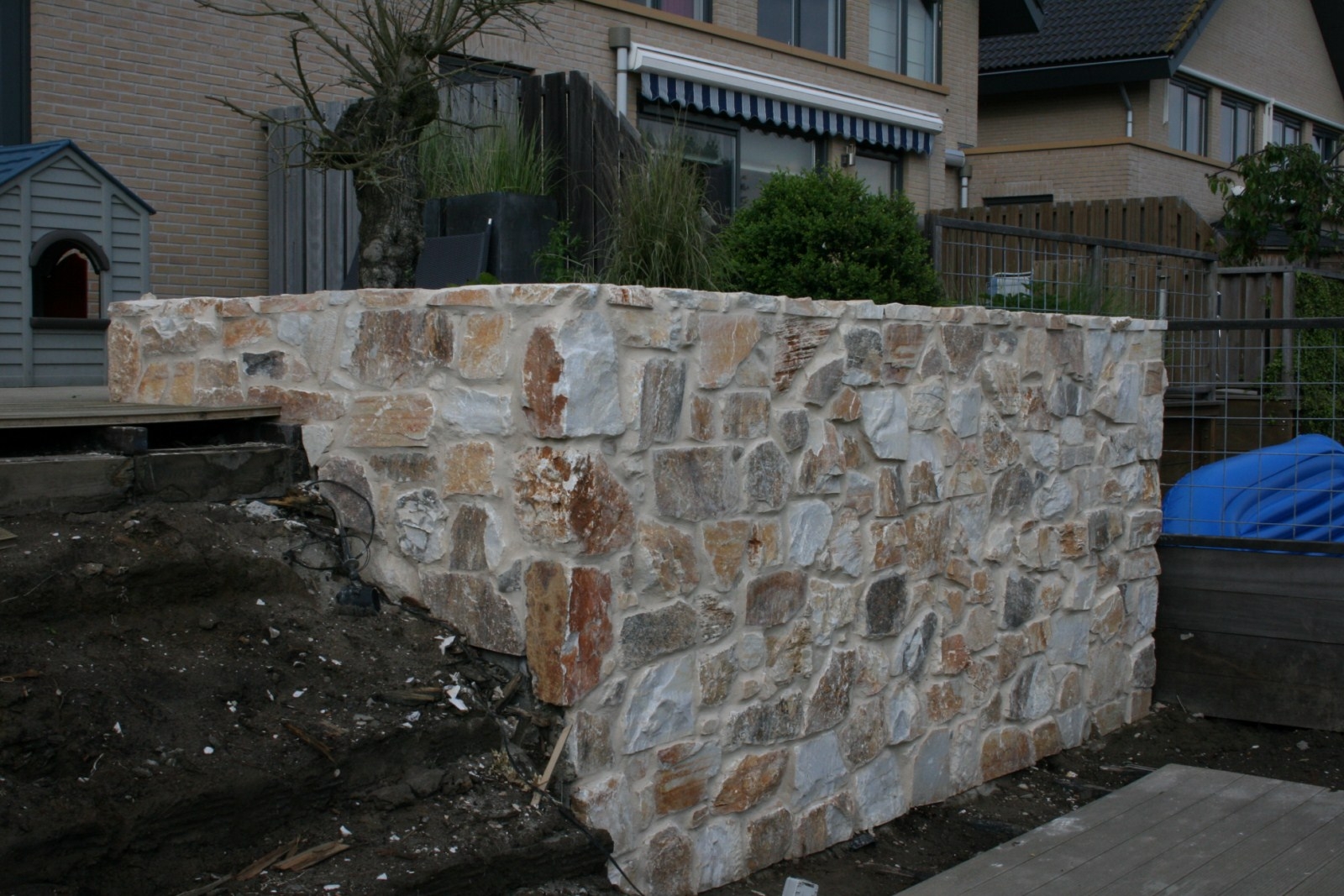 Een muur met de look van grove brokken natuursteen. Toch is dit eenvoudig te realiseren omdat de steen in dikte is bewerkt. Type Rocks  Pepe, voegwerk: ARDEX Zandbeige.