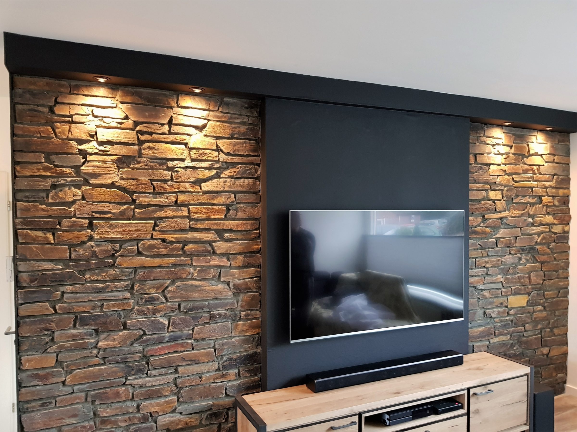 Natuurstenen muur bij de televisie.