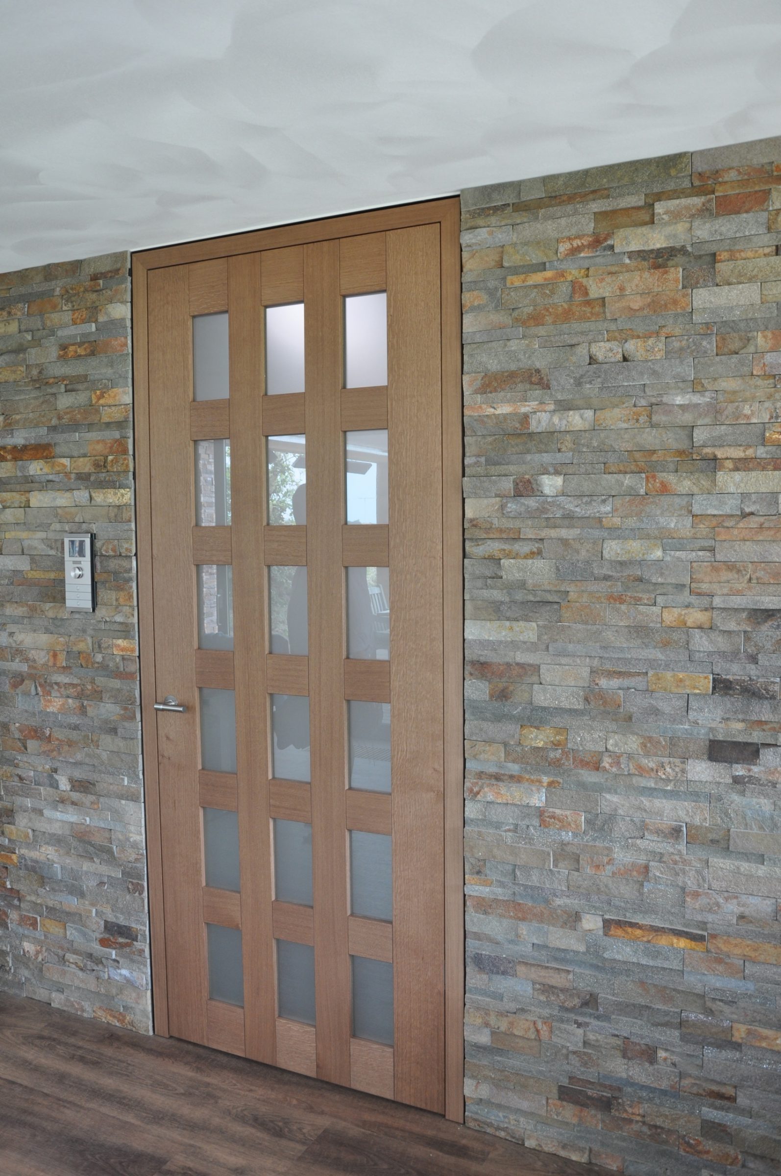 Natuursteenstrips op wand met deur.
