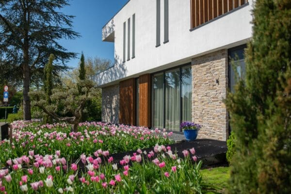 Gevel met Rocks Pedro natuursteenstrips langs een tuin met roze bloemen