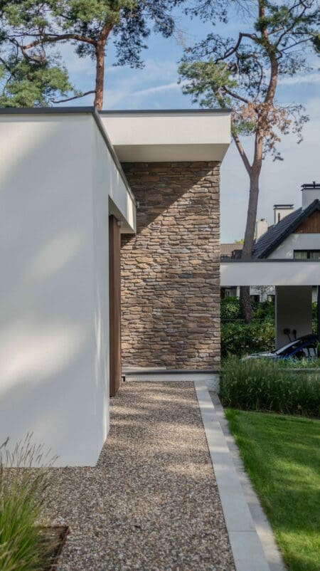 Grindpad langs een witte gevel naar een wand met Blumone steenstrips