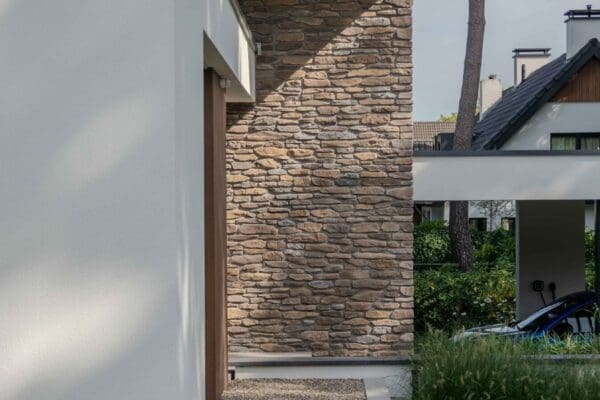 Grindpad langs een witte gevel naar een wand met Blumone steenstrips