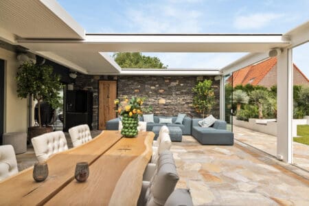 Luxe veranda met een vloer van Flagstones en een wand met Steenstrips.