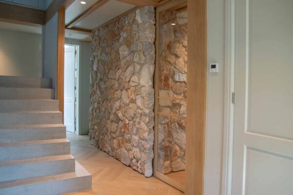 Hal en trap langs een wand met Rocks Grey natuursteenstrips en schuifdeur