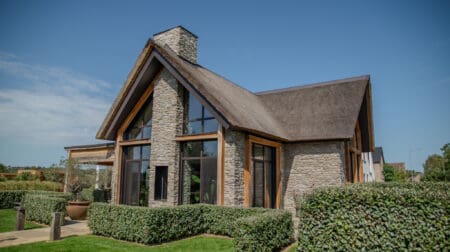 Vrijstaande woning met rieten dak, glas en Cascata steenstrips