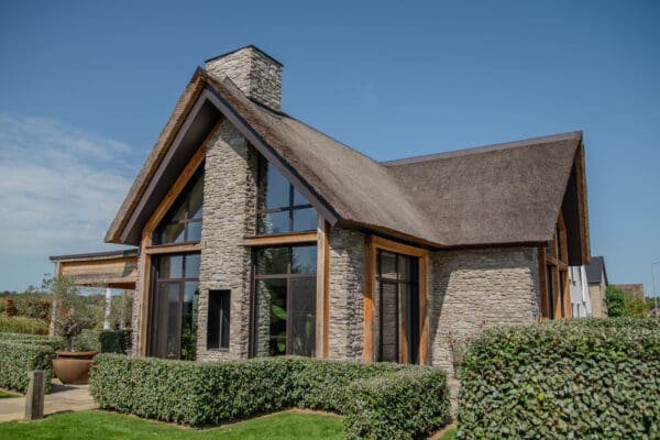 Vrijstaande woning met rieten dak, glas en Cascata steenstrips