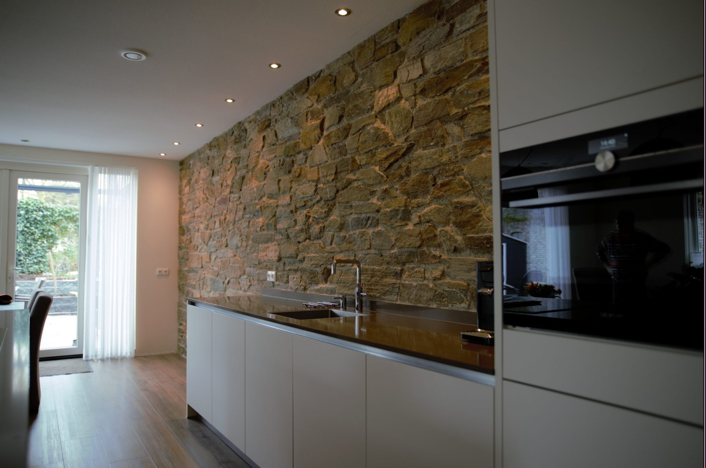 Keuken met Natuurstenen wand en verlichting.