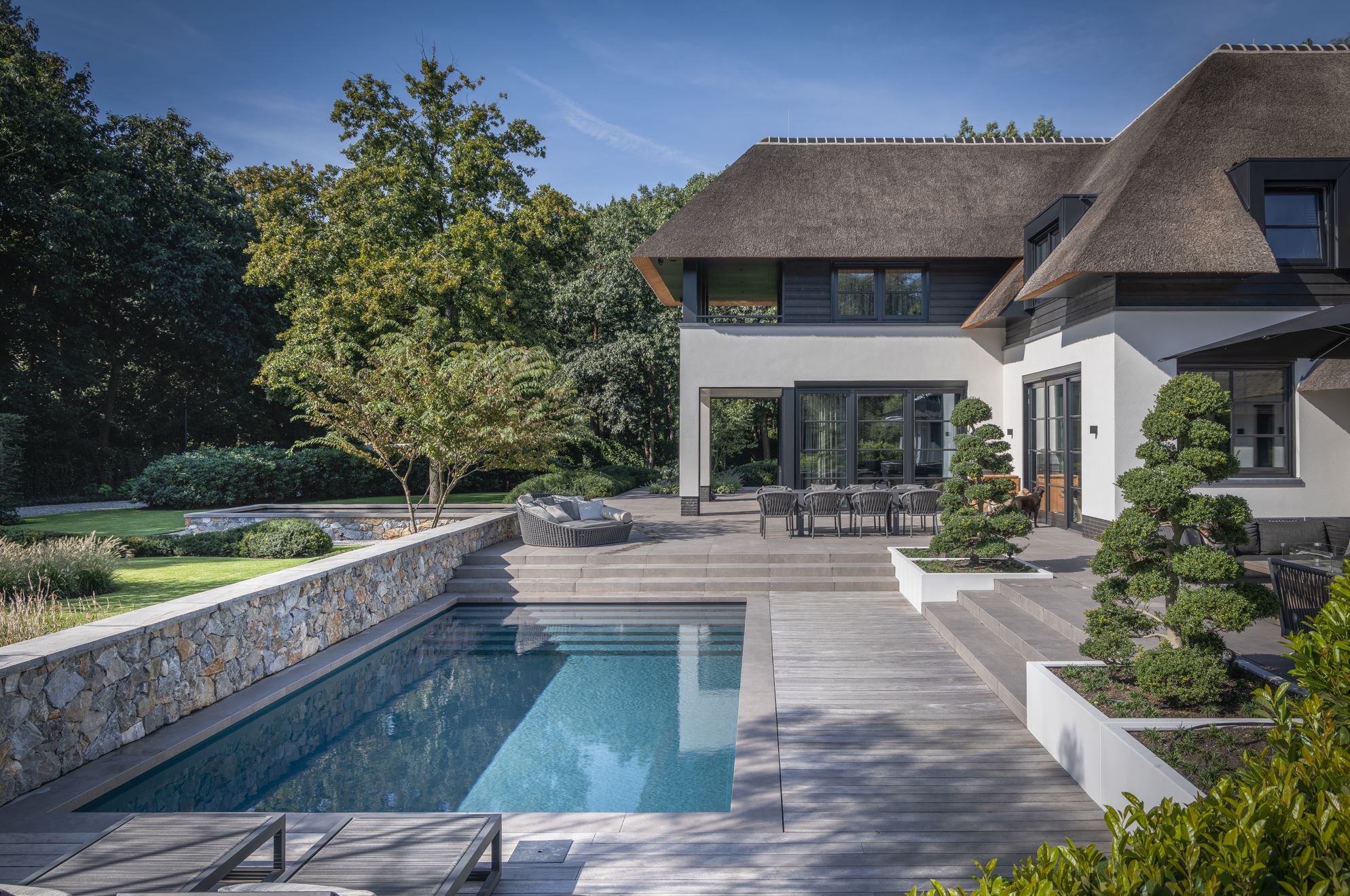Tuinmuren, vijvermuren en zwembadmuren rondom de rietgedekte villa met Natuursteen Rocks Akkron