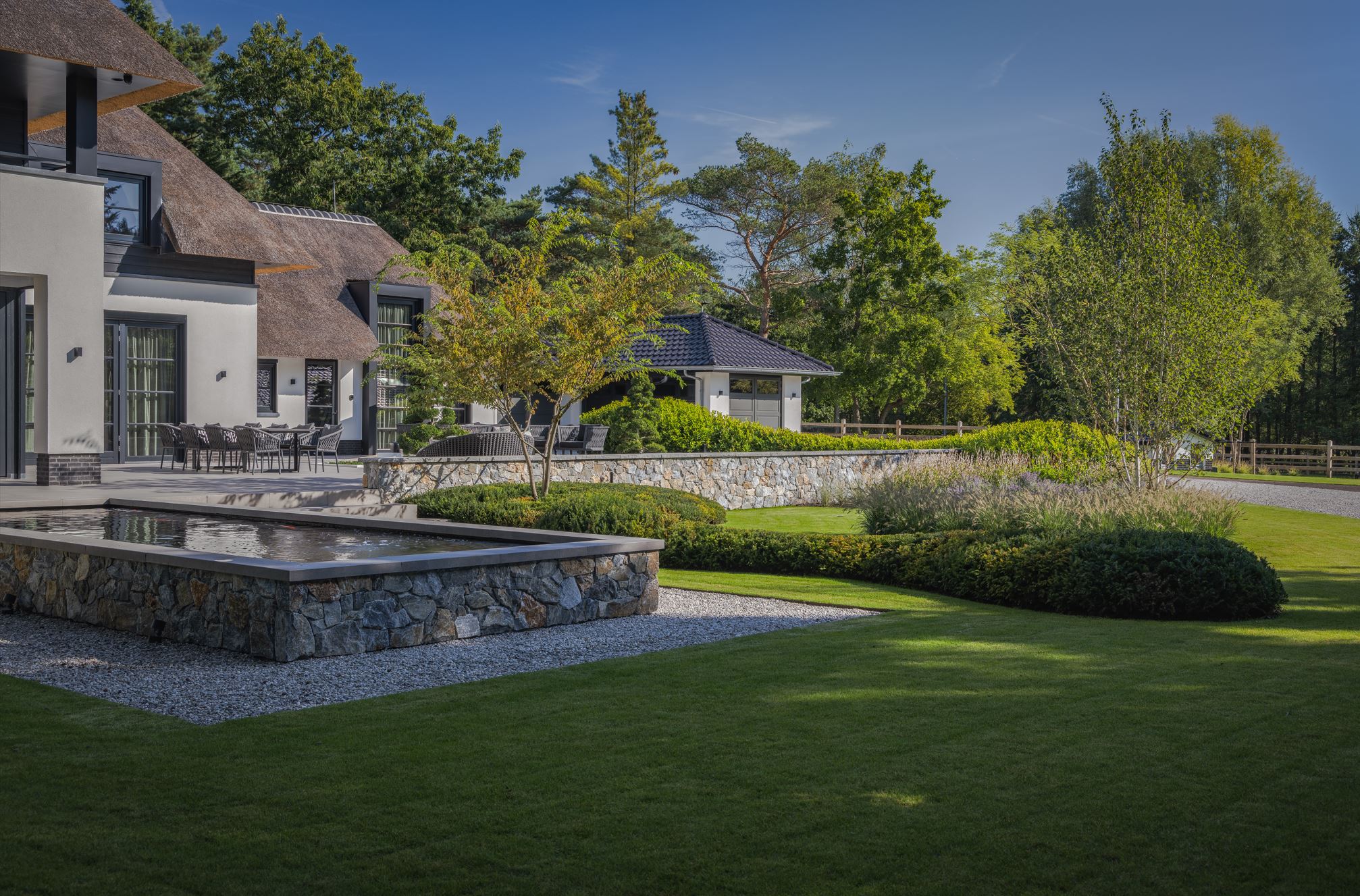 Tuinmuren, vijvermuren en zwembadmuren rondom de rietgedekte villa met Natuursteen Rocks Akkron