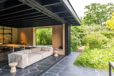 Moderne woonkamer met Mystic Black Flagstones en glazen schuifpui naar de tuin